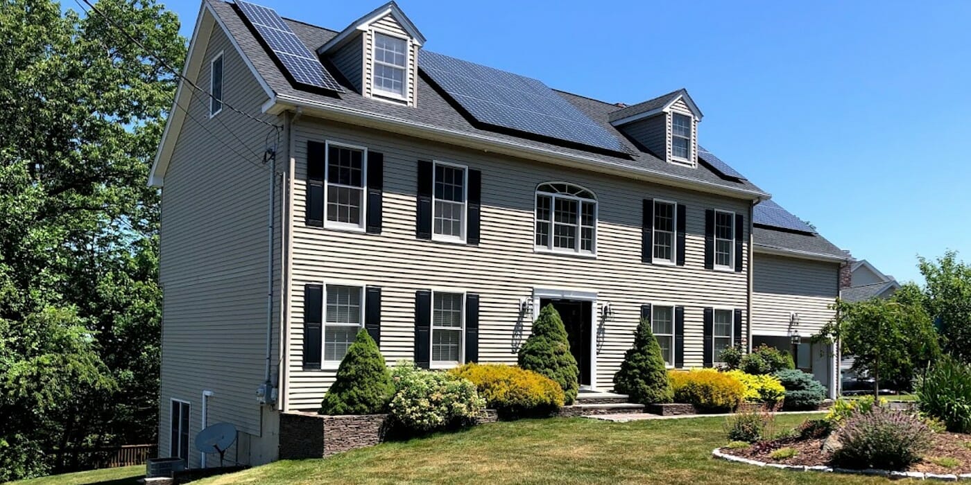 large grey home with solar panels and a new HVAC unit